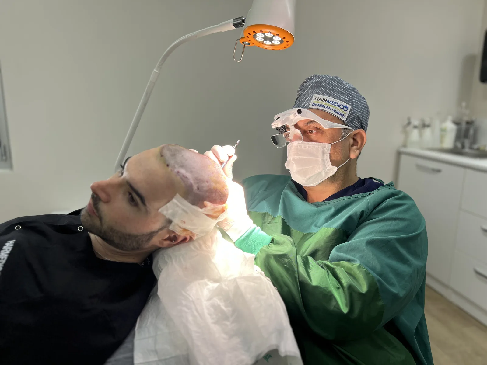 Dr. Arslan Musbeh performing FUE graft extraction under surgical loupes at Hairmedico — the procedure begins only once anaesthesia is fully confirmed