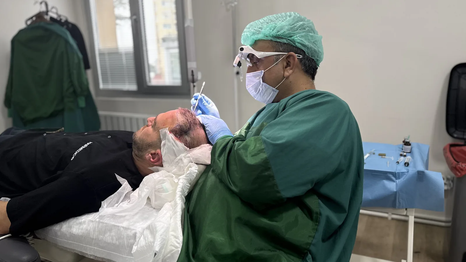 Dr. Arslan Musbeh working on a patient's scalp under surgical loupes at the Hairmedico clinic in Istanbul