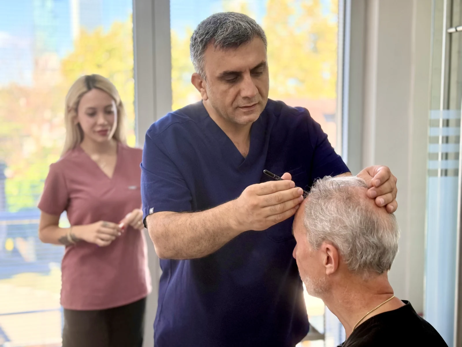 Dr. Arslan Musbeh examining a patient's scalp and donor density during assessment
