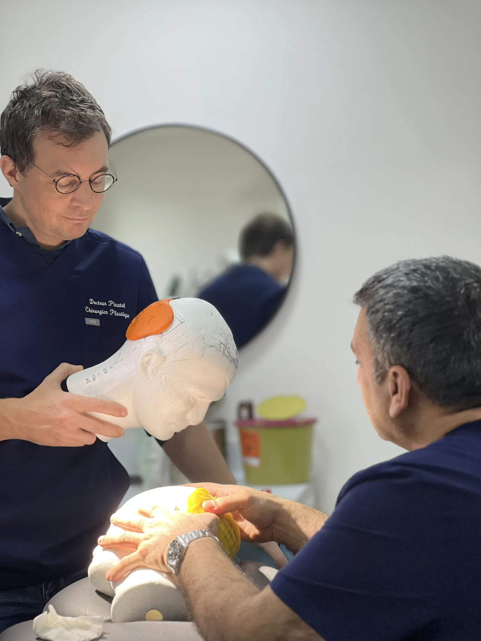 Visiting plastic surgeon studying extraction-zone markings on a training model during a Hairmedico physician training session