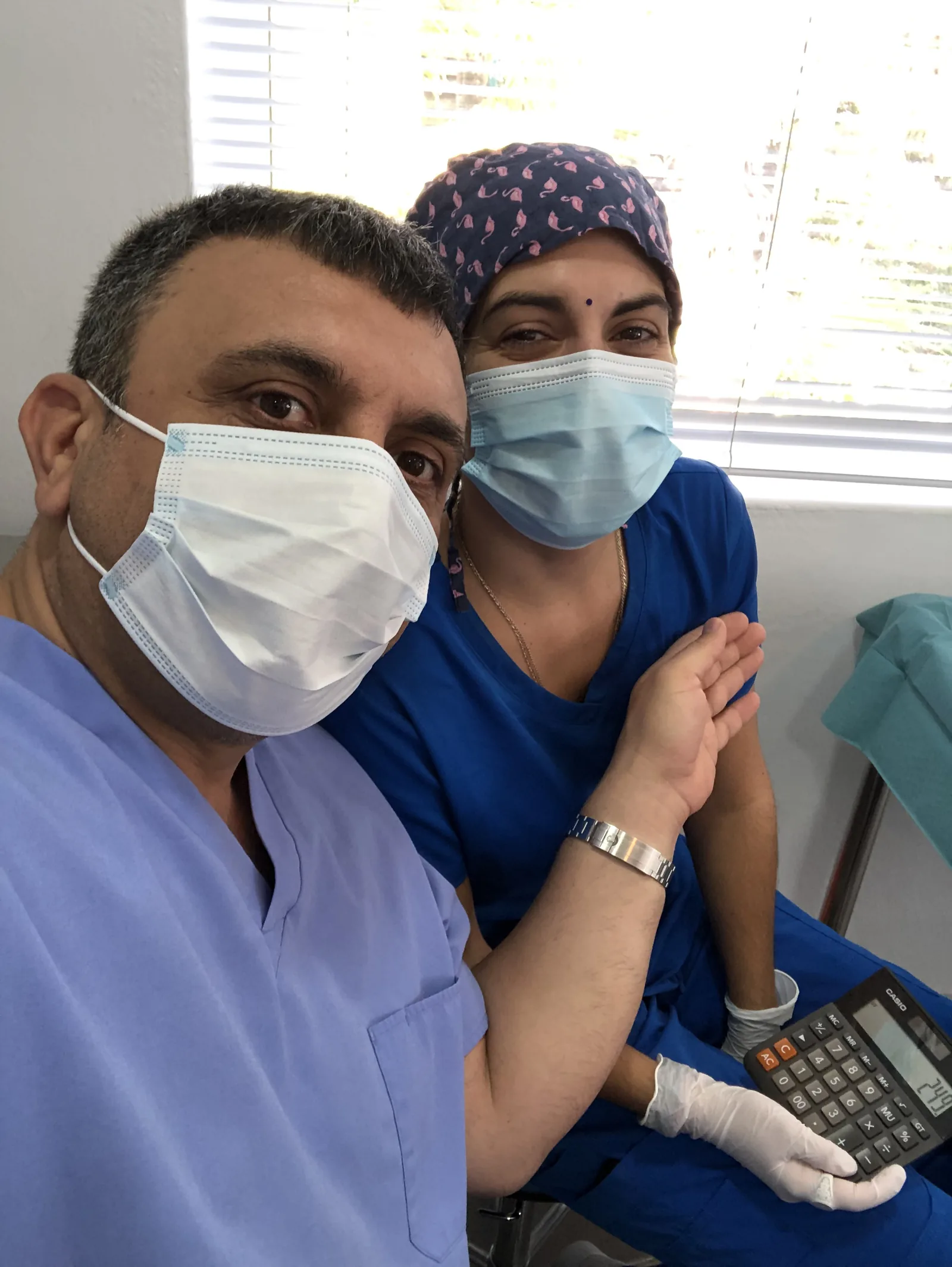 Hairmedico clinical team members in scrubs and masks reviewing a patient case in the treatment room