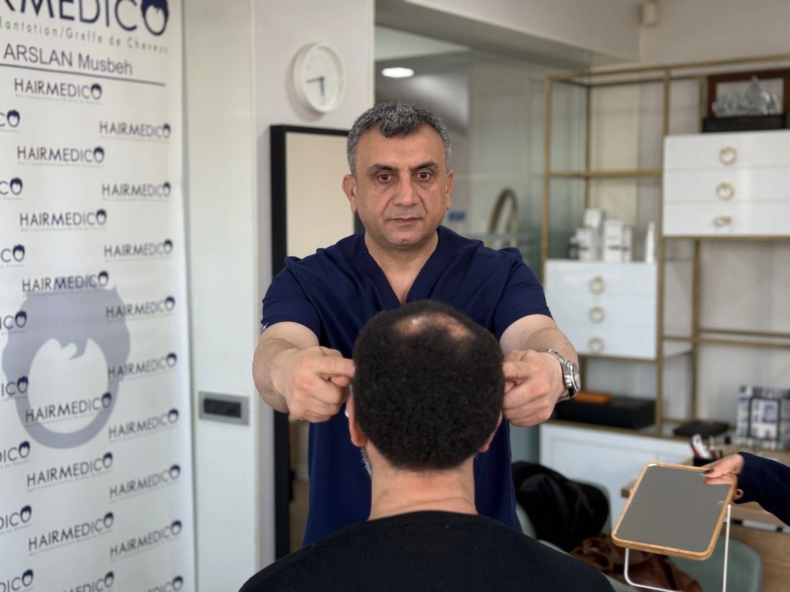 Dr Arslan Musbeh examinant le cuir chevelu d'un patient en consultation