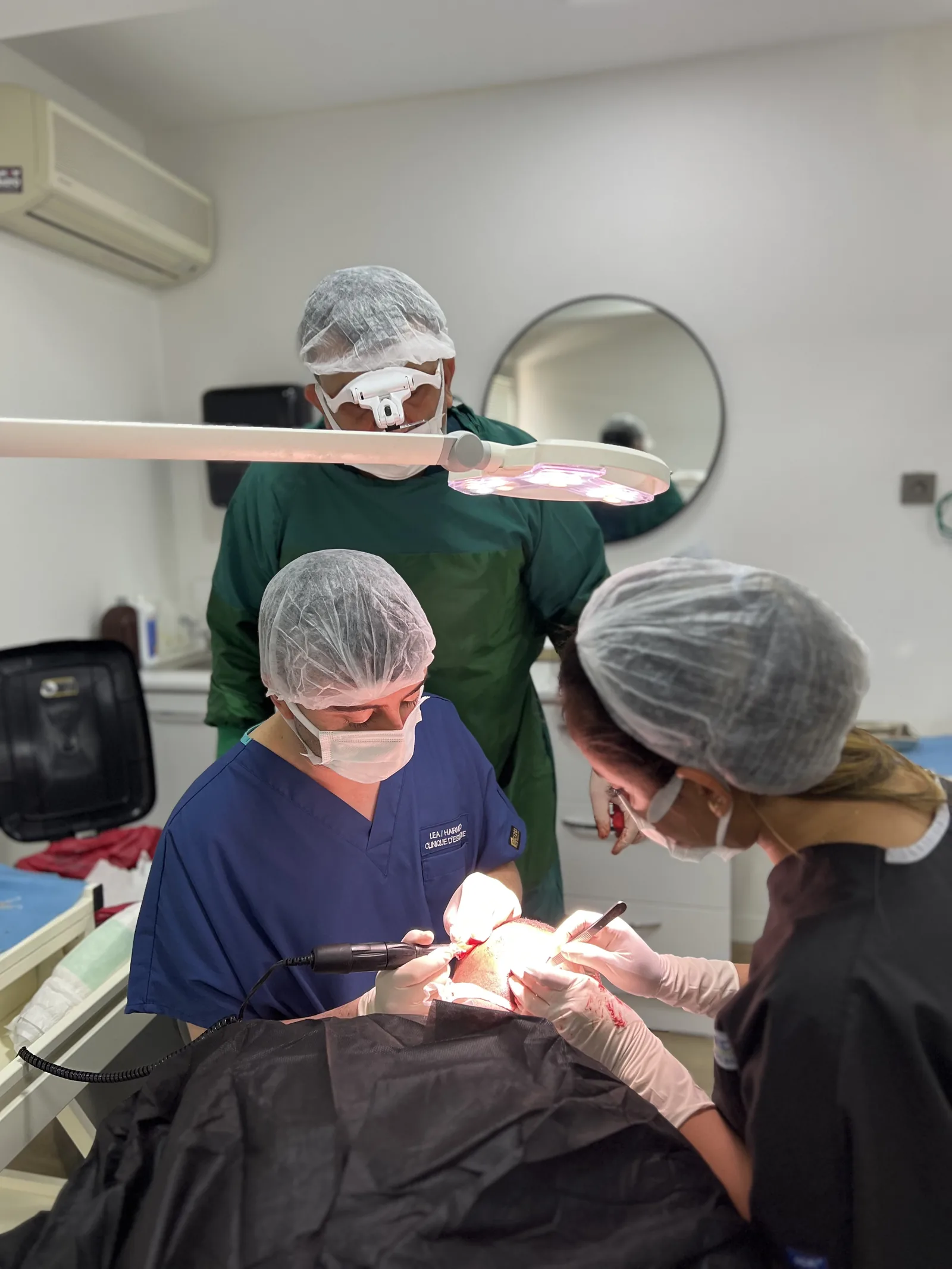 Hairmedico surgical team performing graft extraction under surgical lighting during a live FUE procedure