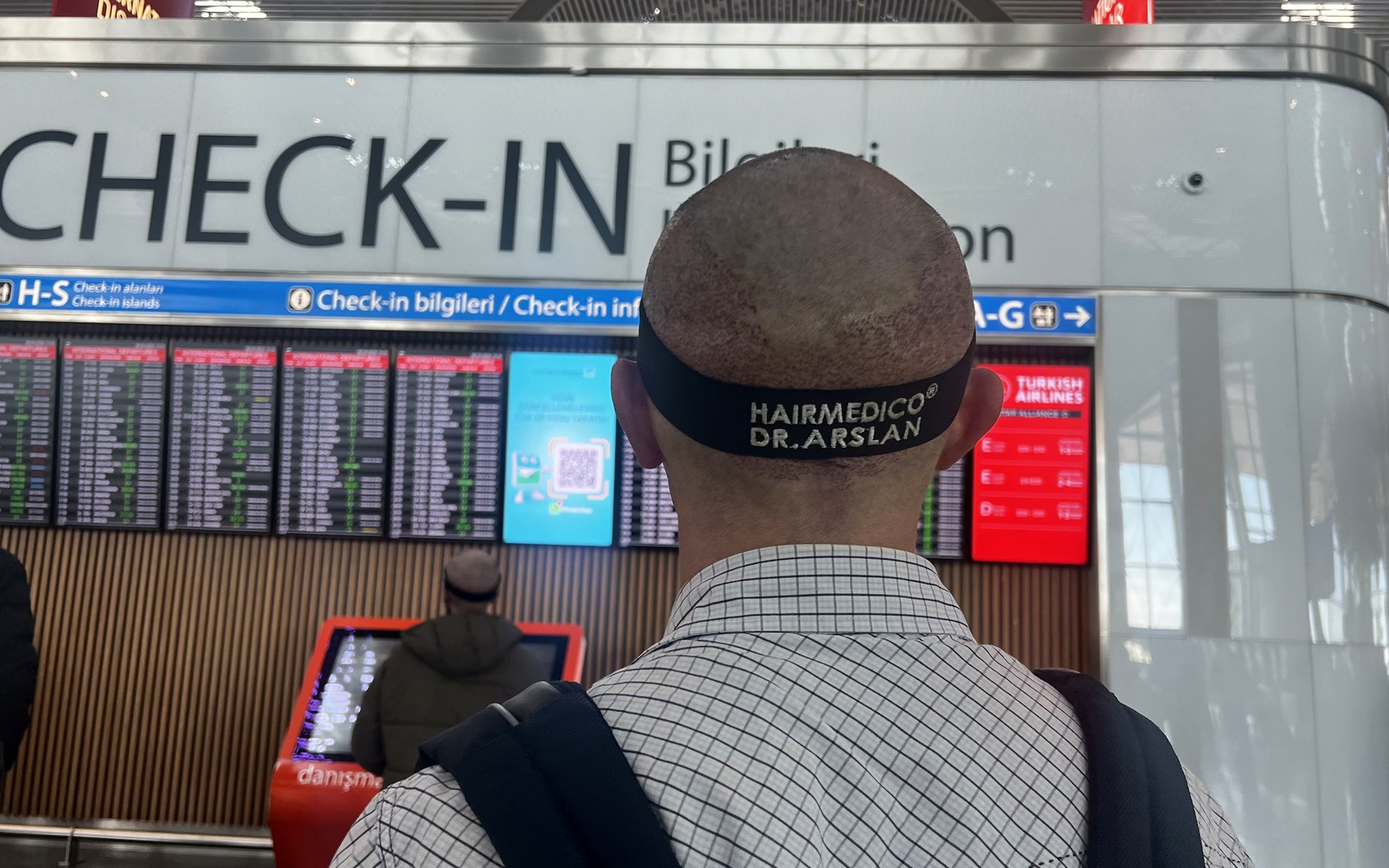 FUE植毛手術後、帰国のためイスタンブール空港のチェックインカウンターで保護用ヘッドバンドを着用するHairmedicoの患者