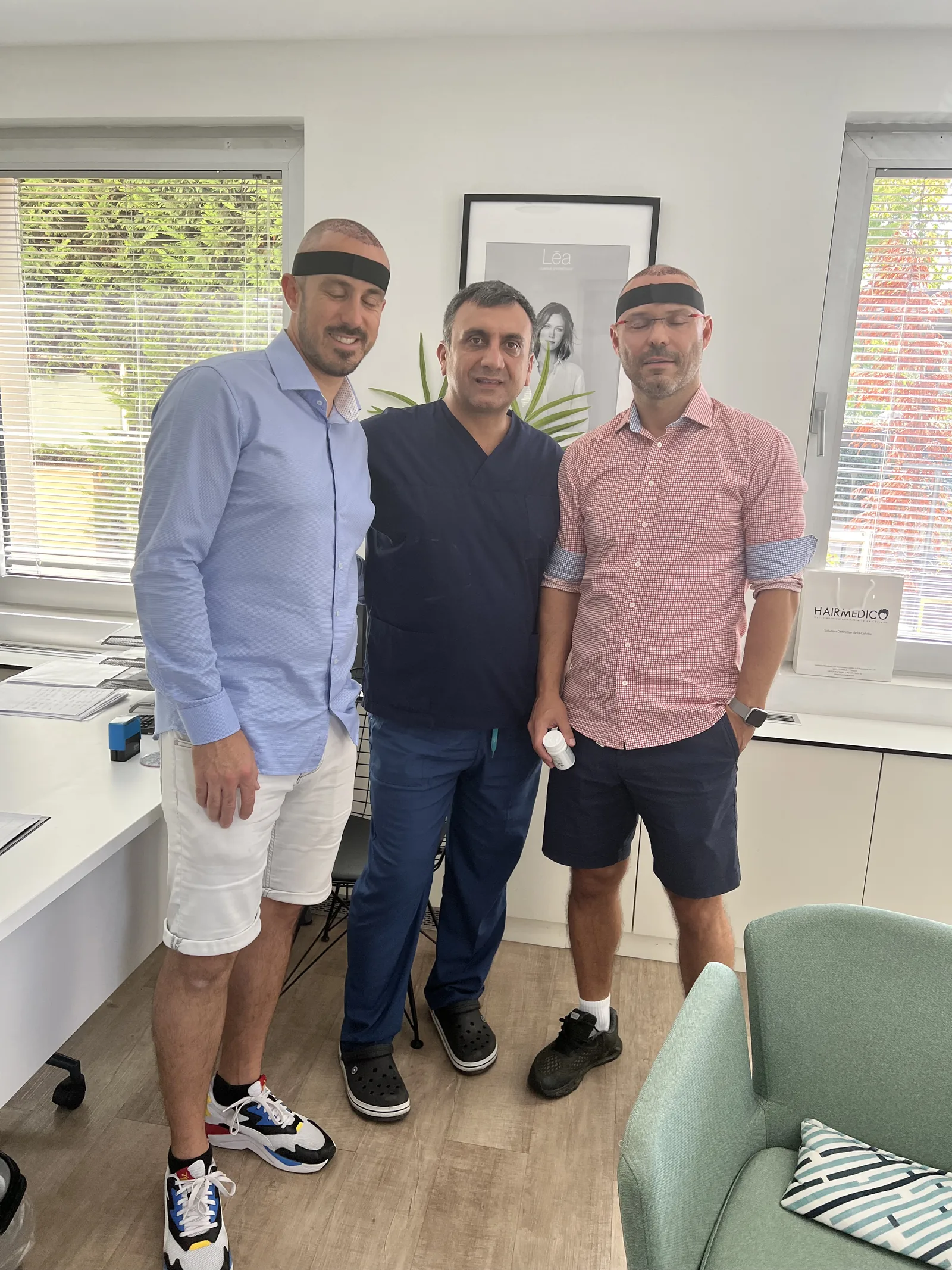 Dr. Arslan Musbeh with two patients wearing post-operative headbands in the Hairmedico clinic reception, Istanbul