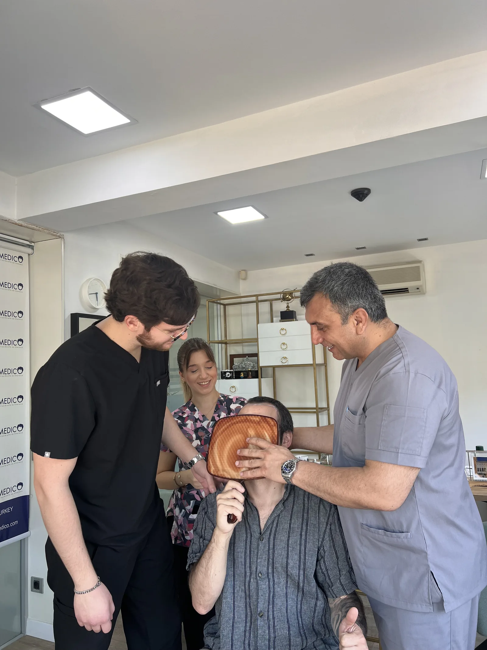 Dr. Arslan's clinical team reviewing a patient's results with a hand mirror at the Hairmedico clinic in Istanbul